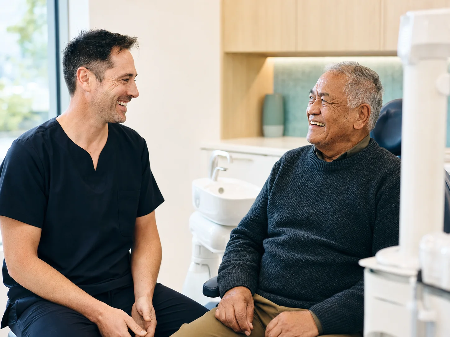 A dentist and an older patient sharing a relaxed conversation after an appointment.